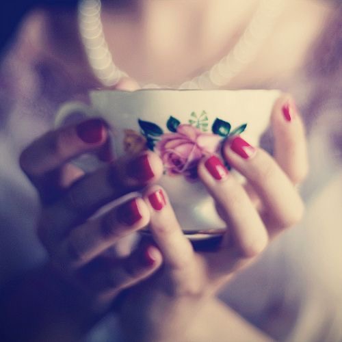 Tea? pretty feminine red nailed hands hold a classic floral teacup